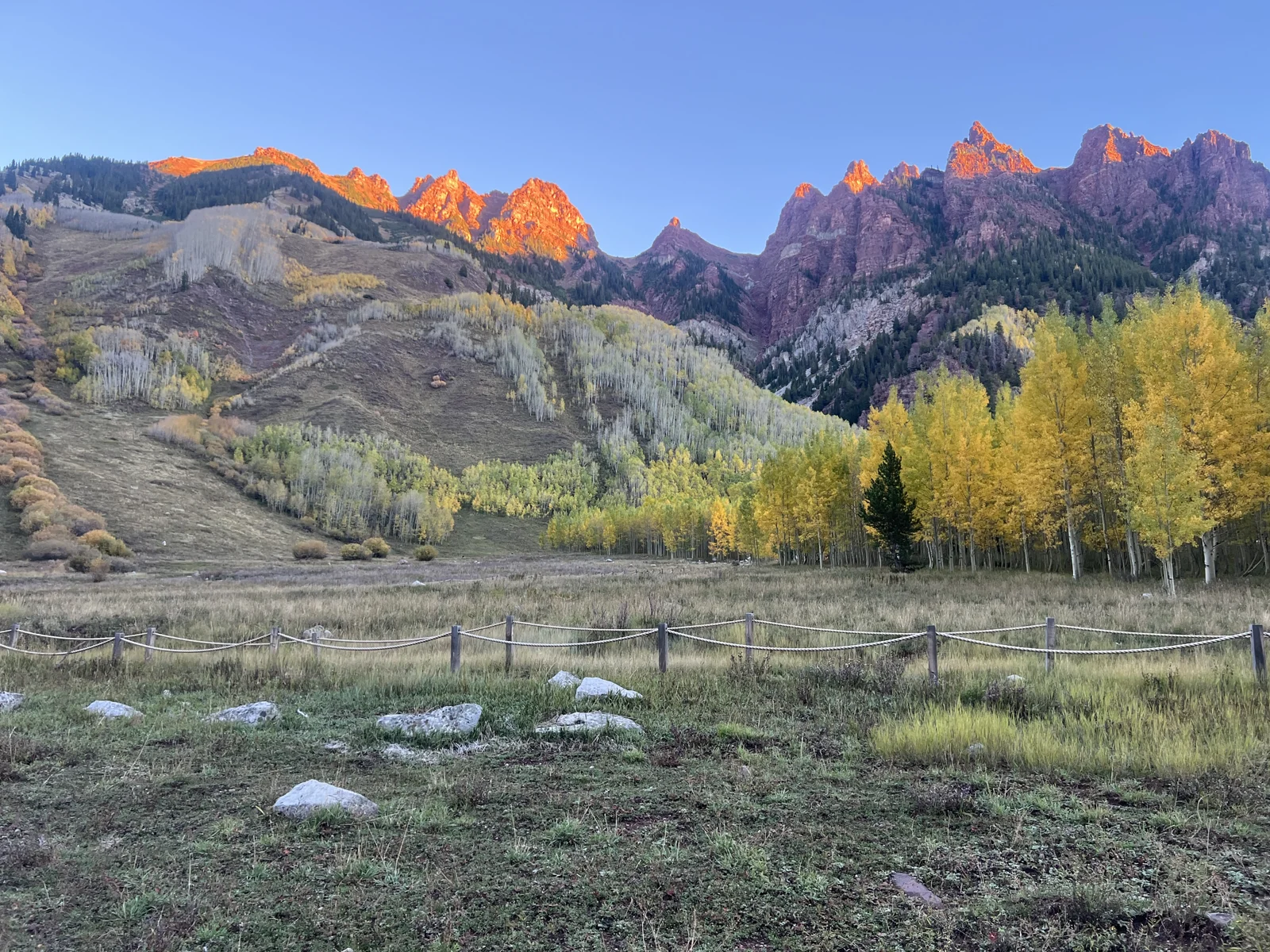 Orange sunrise glow on peaks in the opposite direction from the Maroon Bells