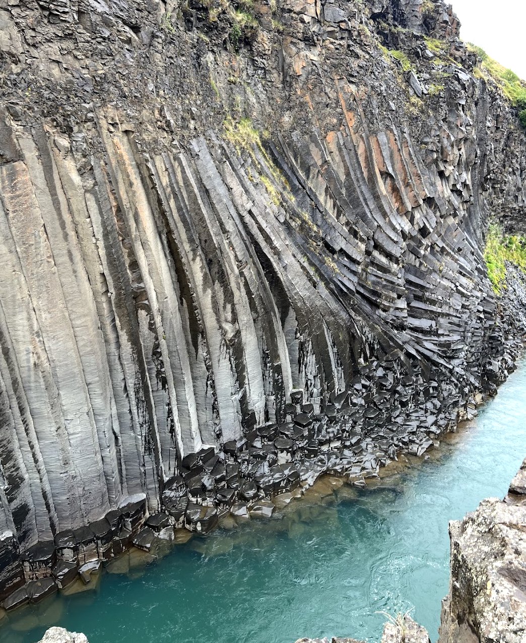 Basalt columns and blue water at Stuðlagil Canyon