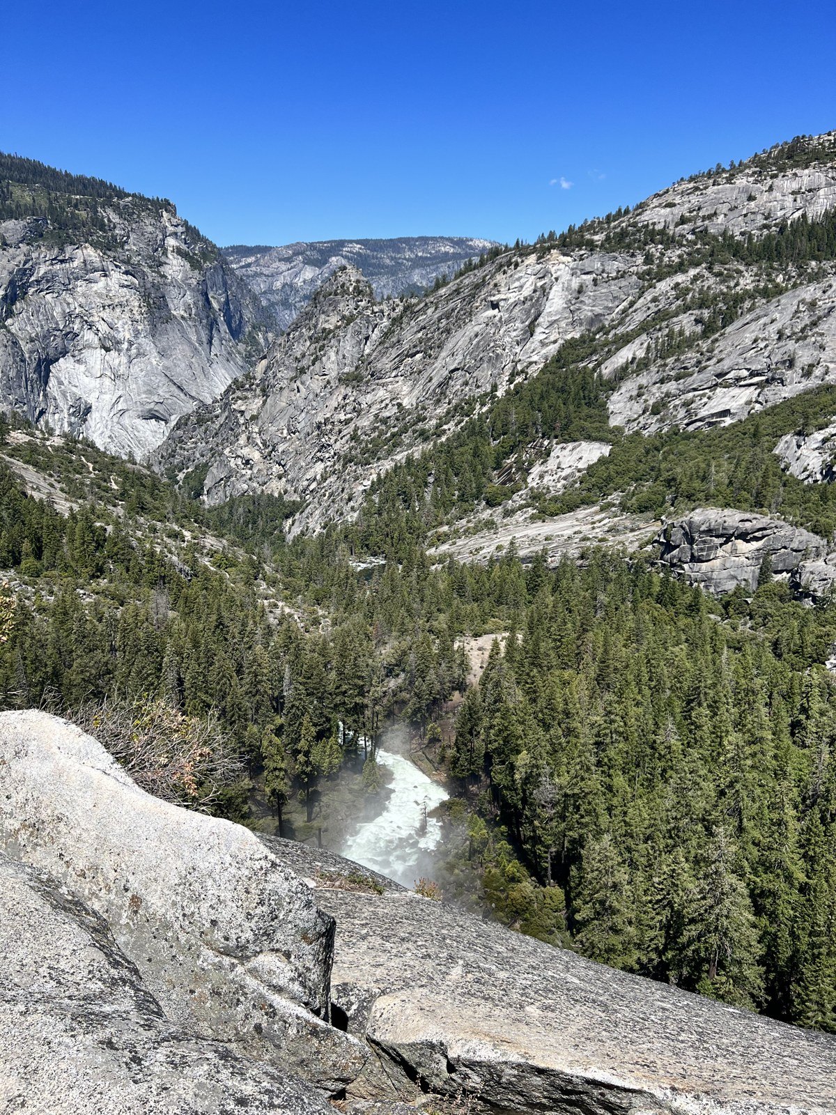 Water rushing over Nevada Fall into a forested granite valley