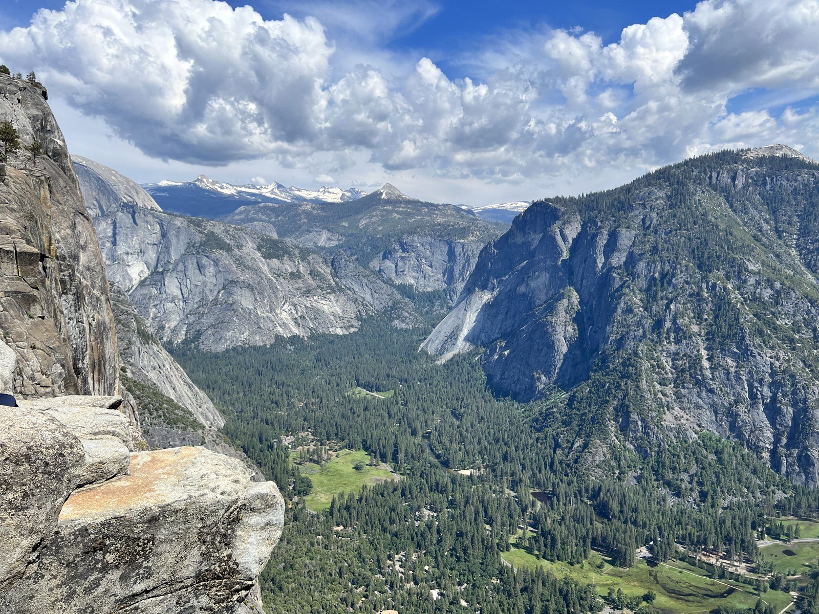 Granite cliffs, forest and distant Half Dome from above Yosemite Valley